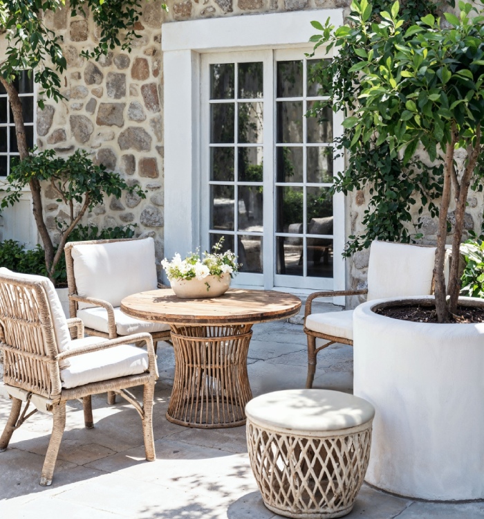 Terrasse aménagée avec salon de jardin, revêtement en pierre et bacs plantés, pour un espace extérieur confortable et élégant